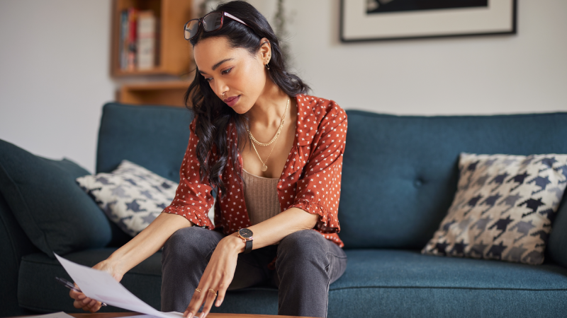 Woman looking at bill in living room