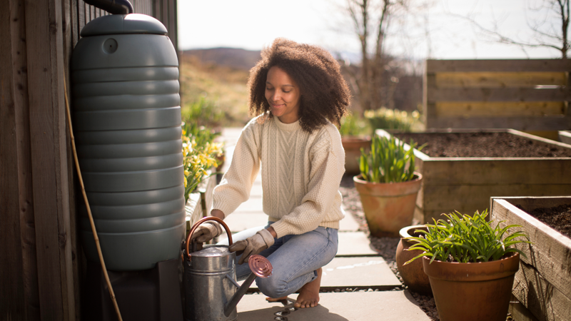 Woman filling a watering can with a water butt